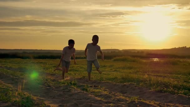 Dvě šťastné dítě běhat a skákat v parku. Na hřišti oba bratři hrají při západu slunce