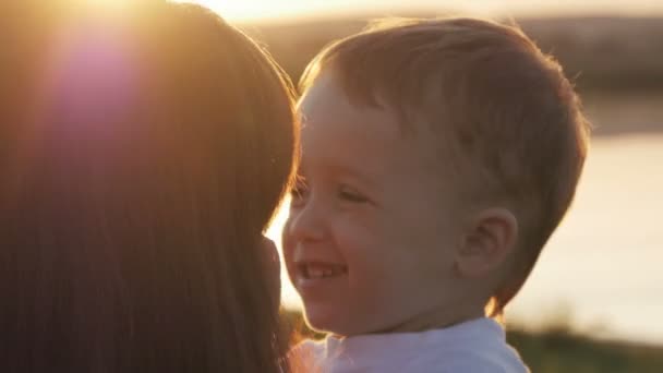 am Abend vor Sonnenuntergang, Baby fühlt sich glücklich und lächelt mit seiner Mutter im Garten