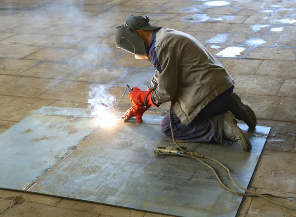 Svetsare i fabriken. En arbetstagare svetsar en stålplåt — Stockfoto