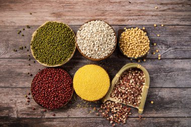 Tahta arka planda farklı tahıl, tahıl ve fasulye koleksiyonu