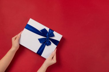 Kırmızı arka plandaki avuçlarda hediye ya da hediye paketi tutan kadınların üst görünümü