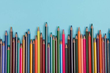 Mavi arkaplanda renkli kalemler dizisi