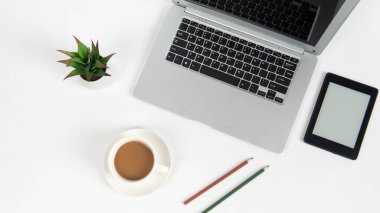 Laptop bilgisayarı, kahve ve ofis malzemeleri olan beyaz ofis masası. Kopyalama alanı olan üst görünüm, düz yatay.
