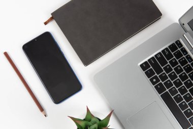 Laptop bilgisayar ve ofis malzemeleriyle dolu beyaz ofis masası. Kopyalama alanı olan üst görünüm, düz yatay.