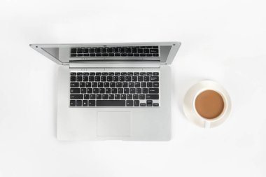 Laptop bilgisayarlı beyaz ofis masası, bir fincan kahve. Kopyalama alanı olan üst görünüm, düz yatay.