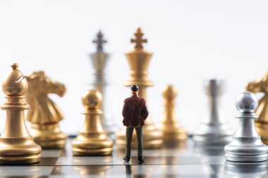 İş ve Rekabet Konsepti. Satranç tahtasının üzerinde satranç taşlarıyla duran minyatür iş adamı figürü