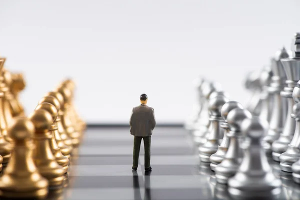 Business and Competition Concept. Businessman miniature figure standing on chessboard with chess pieces