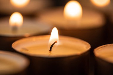 Geceleyin yanan mumlar. Karanlık arka planda parlayan bir sürü mum alevi.