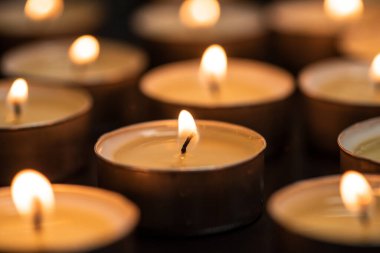 Geceleyin yanan mumlar. Karanlık arka planda parlayan bir sürü mum alevi.