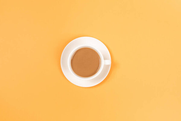 A cup of coffee on yellow background, top view