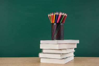 Kara tahta arkaplan kopyalama alanı olan ders kitabı yığını üzerindeki kalem