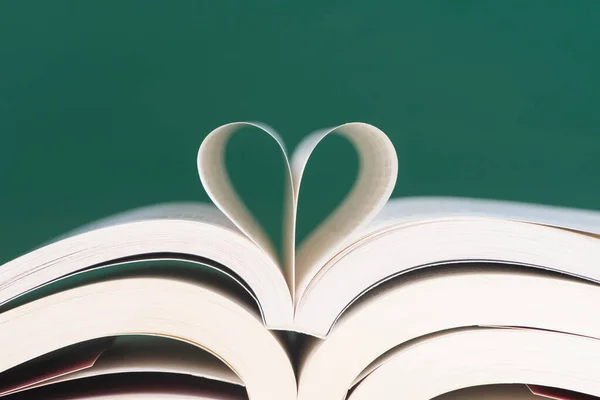 open books with a heart on a green background