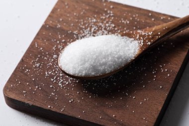 Ahşap kaşık arka planında bir yığın tuz.