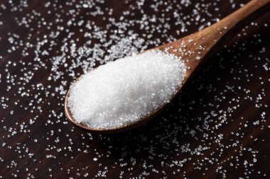 Tahta arka planda beyaz şekerli kaşık