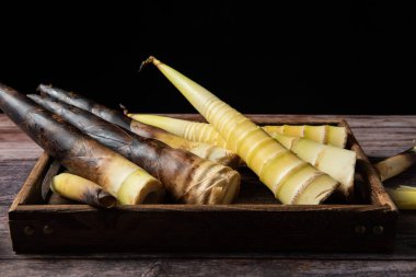 Tahta arka planda taze toplanmış bambu filizleri