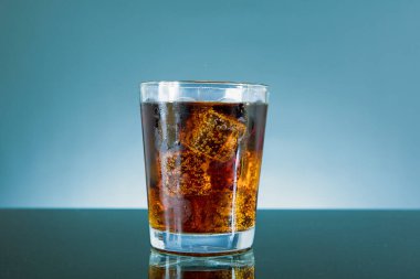 Mavi arka planda izole edilmiş cam şişede buzlu kola..