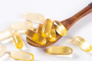 Beyaz zemin üzerinde altın balık yağı kapsülleri