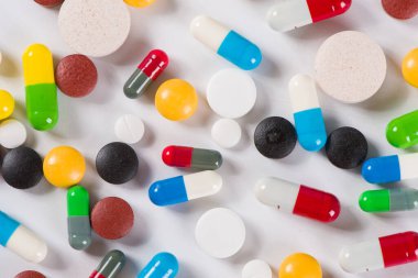 Beyaz arka planda çeşitli ilaç hapları, haplar ve kapsüller.