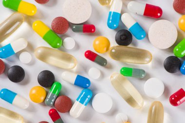 Beyaz arka planda çeşitli ilaç hapları, haplar ve kapsüller.