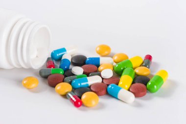 Beyaz arka planda çeşitli ilaç hapları, haplar ve kapsüller.