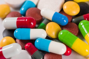 Beyaz arka planda çeşitli ilaç hapları, haplar ve kapsüller.