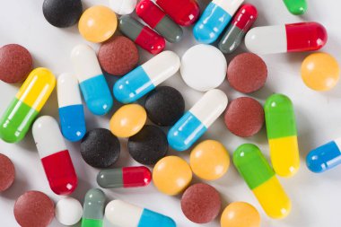 Beyaz arka planda çeşitli ilaç hapları, haplar ve kapsüller.