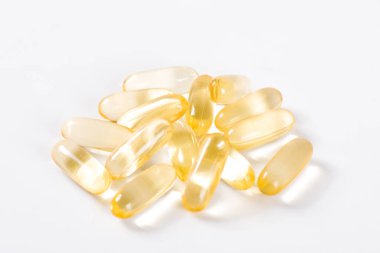 Beyaz zemin üzerinde altın balık yağı kapsülleri