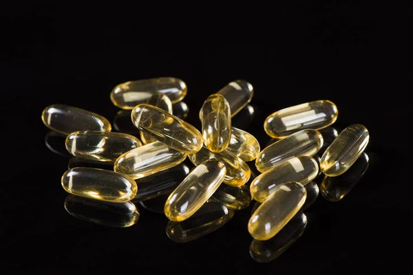 gold fish oil capsules on white background