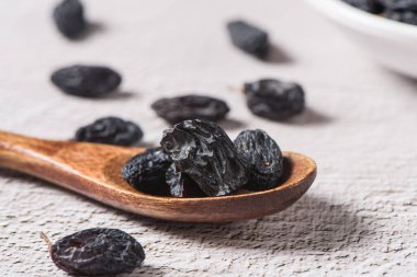 Dried fruits, pile of black raisins on table.