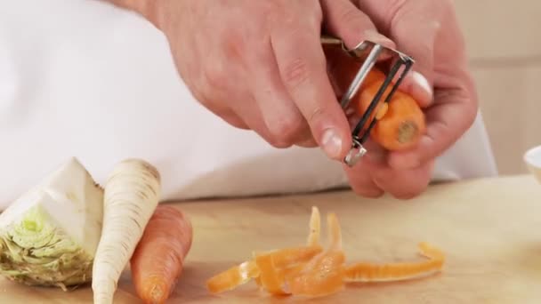 Морковь чистят на столе — стоковое видео