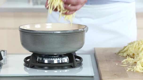 Geriebener Käse wird in einen Fonduetopf gegeben — Stockvideo