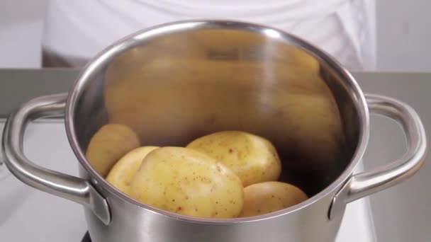 Pouring water into a pan of potatoes — Stock Video