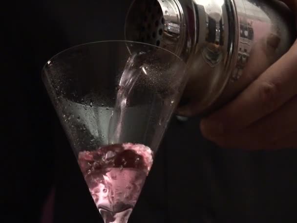 Bartender straining Cosmopolitan into a glass — Stock Video