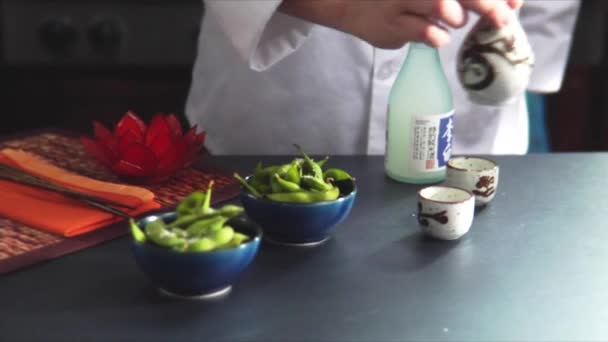 Gieten van sake naast sojabonen — Stockvideo