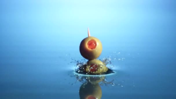 Оливки на коктейльной палочке падают в воду — стоковое видео