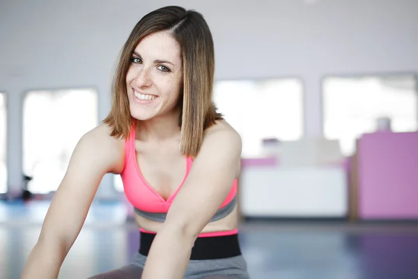 Mujer sonriente haciendo ejercicios en la estera en el gimnasio —  Fotos de Stock