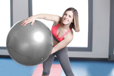 spor salonunda egzersiz topu ile gülümseyen kadın.