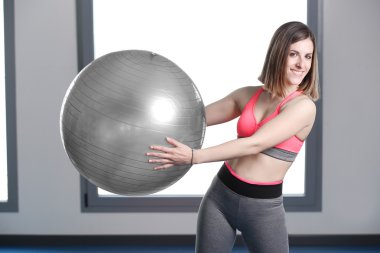 spor salonunda egzersiz topu ile gülümseyen kadın.