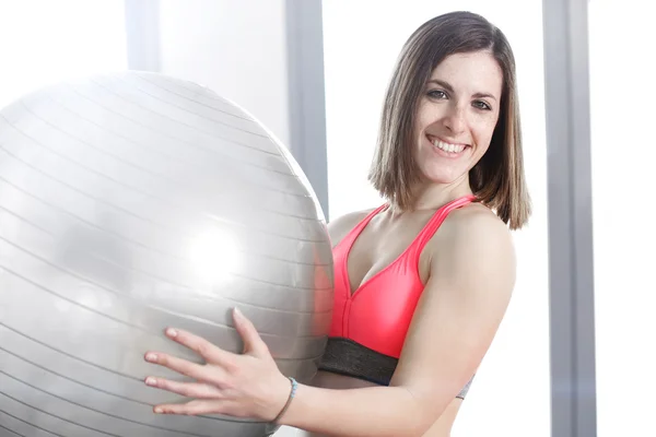 Mujer sonriente con pelota de ejercicio en el gimnasio . —  Fotos de Stock