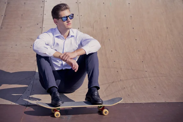 Yound kavkazské obchodní muž relaxační na skateboard . — Stock fotografie