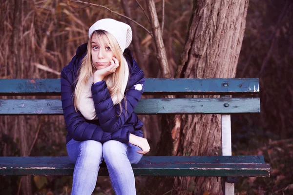 Молодая блондинка скучающая девушка на скамейке — стоковое фото