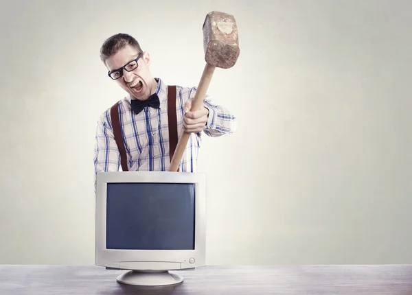 Young angry nerd destroying old computer monitor — Stock Photo, Image