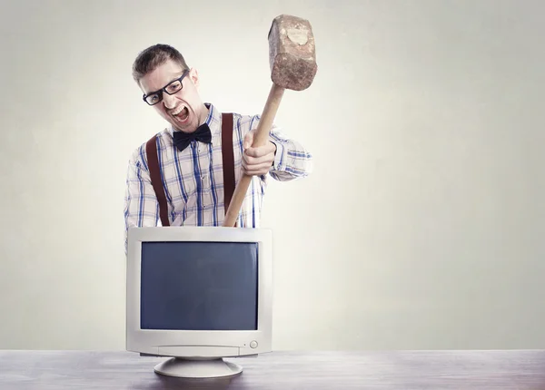 Joven nerd enojado destruyendo viejo monitor de computadora — Foto de Stock