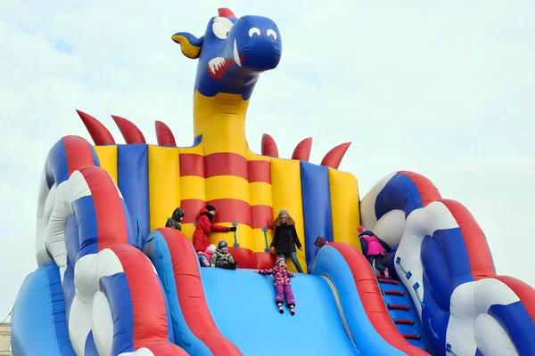 Children ride on inflatable colorful slide in the shape of a dra — Stock Photo, Image
