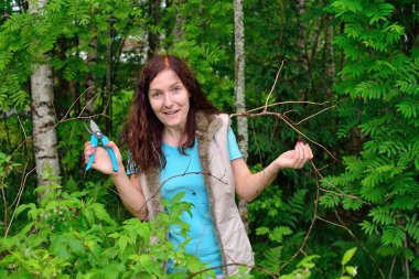 Kız bahçıvan gülüyor ve makası kuru bir ra'nın dallara keser