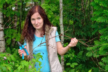 Kız bahçıvan gülümsüyor ve makası keser daldan Kuru 