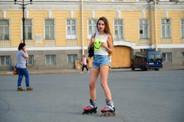 Şortlu güzel bir kız yazın St. Petersburg 'da Palace meydanında patenle kayıyor..