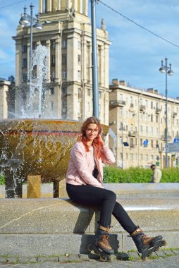 Patenli güzel bir öğrenci St. Petersburg 'daki Halk Kütüphanesi binasının yakınındaki çeşmede oturuyor.