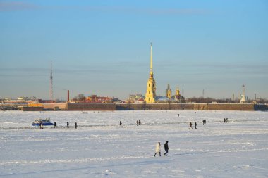MOE teknesi, kışın Saint-Petersburg 'da güneşli bir günde Peter ve Paul kalesinin arka planında Neva nehrinin buzunda olmanın tehlikesi konusunda uyarıyor.