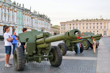 İnsanlar namlu freninde kırmızı karanfil olan silahlara bakar ve...